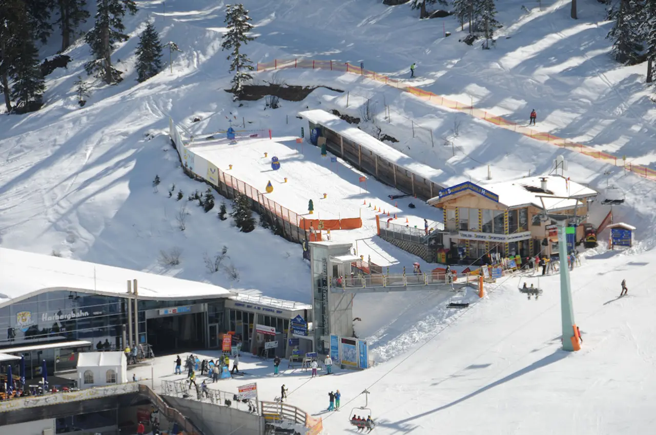 Horbergbahn Bergstation mit Fahrstuhl und dem Haus von Sport Schiestl, Weg zum Sammelplatz in drei Schritten markiert